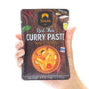 Hand holding a package of Siam Red Thai Curry Paste against a white background